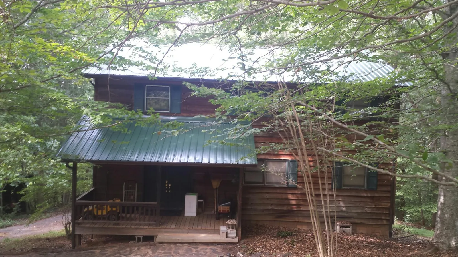 Green metal roof and covered porch on a log cabin in Chugwater
