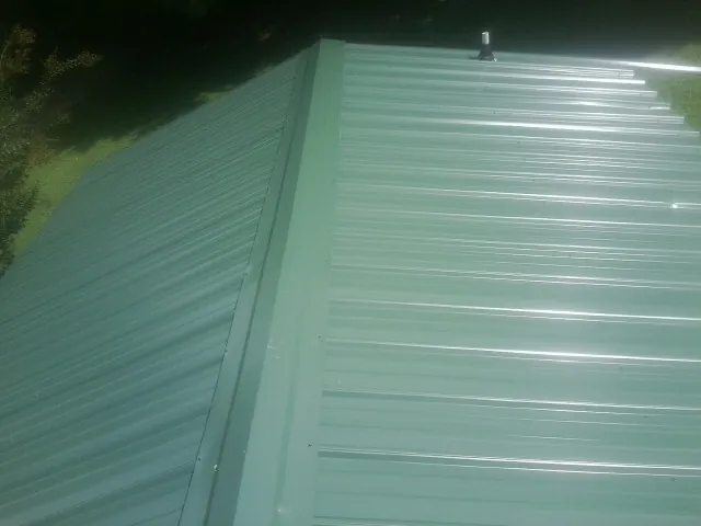 New green metal panels meeting at the ridge of a roof — Flat Roof Repair work by our crew in Chugwater
