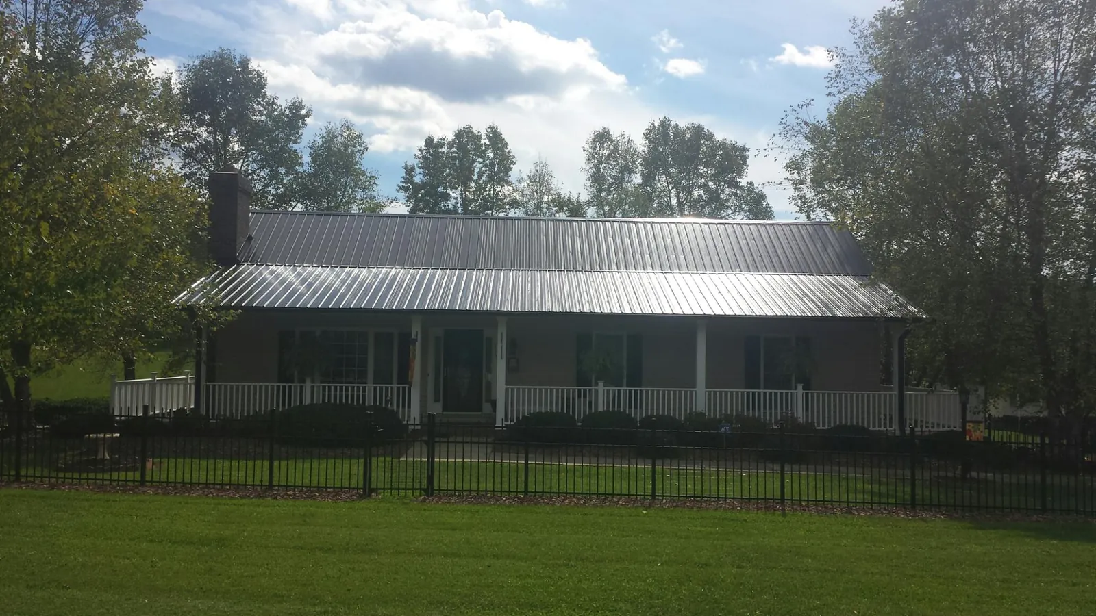 Gray metal roof on a brick ranch with a full width front porch — Gutter Guard Installation work by our crew in Chugwater