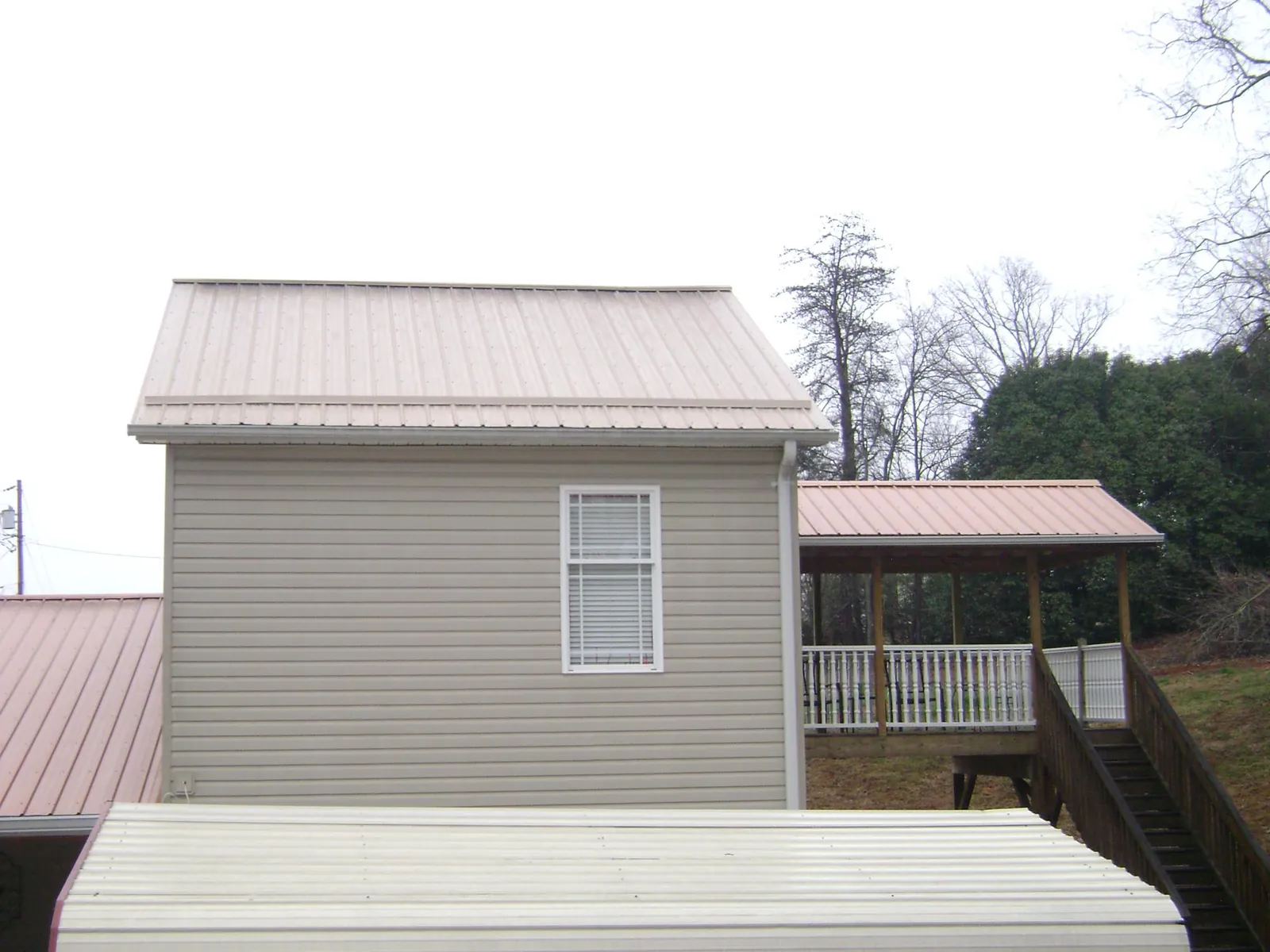 Tan metal roofs on a two story addition and attached porch, from a Roof Replacement job in Chugwater