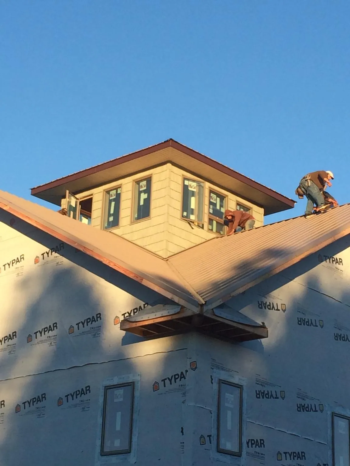 Roofers working around a rooftop cupola on a new metal roof at sunset — Roof Waterproofing in Chugwater by Roofing Brothers